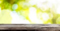 Wooden table against lush green bokeh summer or spring background Royalty Free Stock Photo