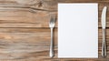 Rustic wooden table with a blank menu, fork, and knife creating white space for a mockup Royalty Free Stock Photo