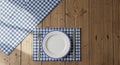 Rustic wooden table setting with gingham place mat and white plate ready for meal Royalty Free Stock Photo