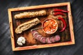 Rustic wooden tray with simple Balkan foods - ajvar spread, bread, meat, garlic and chilli peppers