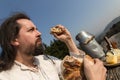 Rustically man with long hair eating bread in the nature Royalty Free Stock Photo