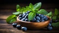 Rustically staged ripe blueberries and fresh spearmint in clay bowl on wooden table