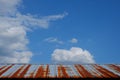 Rusting tin roof of a barn against a beautiful blue sky with puffy white clouds Royalty Free Stock Photo