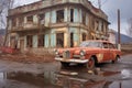 rusting vintage car parked in front of a dilapidated building Royalty Free Stock Photo