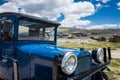 A rusty abandoned jalopy truck sits in a field in the ghost town