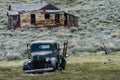 A rusty abandoned jalopy truck sits in a field in the ghost town