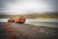 Rusty and abandoned old ship wreck from world war two laying on land in Mjoifjordur in Iceland.