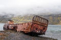 Rusty and abandoned old ship wreck from world war two laying on land in Mjoifjordur in Iceland.