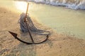 RUSTY ANCHOR WET BEACH SAND AND WHITE SEA WAVE FOAM