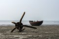 Rusty anchor on a wet beach with traditional country boat in background