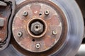 Rusty back car wheel hub with five bolts and brake disc at tire shop. Car without a wheel while replacing on the tire service