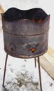 a rusty barrel with burning coals stands on the snow. Fire from a barrel.