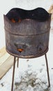 a rusty barrel with burning coals stands on the snow. Fire from a barrel.