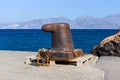 Rusty bitt with a chain on the berth. Royalty Free Stock Photo