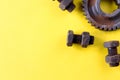 Rusty bolts, nuts and gear wheel made of chocolate isolated on yellow background