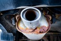 Rusty car exhaust muffler with a through hole, close-up. Corrosion on a metal exhaust pipe after winter. The reaction of salts and