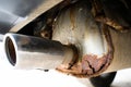 Rusty car exhaust muffler with a through hole, close-up. Corrosion on a metal exhaust pipe after winter. The reaction of salts and
