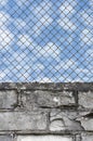 Rusty chain link fence, white grey brick wall texture background, blue summer sky clouds, vertical old weathered security pattern Royalty Free Stock Photo