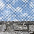 Rusty chain link fence, white grey brick wall texture background, blue summer sky and clouds, vertical  old aged weathered Royalty Free Stock Photo