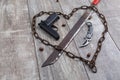 Rusty chain in the shape of heart and machete on a wooden background. Top view from an angle