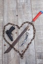 Rusty chain in the shape of heart and machete on a wooden background. View from above