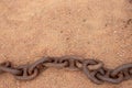 Rusty chains. Selective focus on a old big rusty ships anchor chain in the sand near the sea with large copy space. Abstract Royalty Free Stock Photo