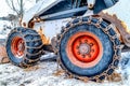 Rusty chains wrapped on the heavy duty black tires of an old snow bulldozer