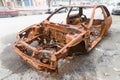 Rusty chassis of a burnt car abandoned by the side of the street Royalty Free Stock Photo