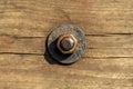 Rusty corroded nut with a washer on a threaded bolt on an old cracked worn wooden surface