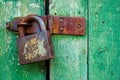 Rusty door hinge and old lock on green wood door with cracked and scratch. Close-up horizontal grunge texture Royalty Free Stock Photo