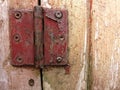 Rusty door hinge on scratched up wooden door