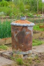 Rusty garden incinerator with plants in background Royalty Free Stock Photo