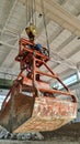 Rusty grab bucket or clamshell hanging on crane in empty industrial plant