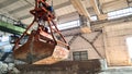 Rusty grab bucket or clamshell hanging on crane in empty industrial plant