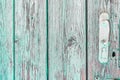 Rusty handle on wooden door with cracked peeling green paint. Texture of weathered painted wood with copy space for your design. Royalty Free Stock Photo