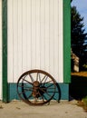 A rusty horse carriage wheel against a white-painted barn. Royalty Free Stock Photo