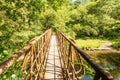 Rusty iron bridge, among the trees, over the upper reaches of the River Severn in the Llanidloes countryside, Wales Royalty Free Stock Photo