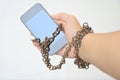 Rusty iron chain that ties together hand and smart phone Royalty Free Stock Photo