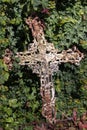 A rusty iron crucifix sits against an ivy-covered wall