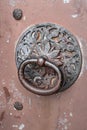 Rusty iron door knocker with carved pattern on the door of an old building Royalty Free Stock Photo