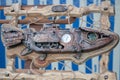 Rusty iron fish in a wooden frame wrapped with a rope, with a clock in the middle, white and blue background