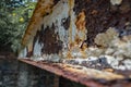 A rusty iron girder with flaking white paint.