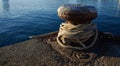 Rusty iron mooring bollard with nuatical ropes.