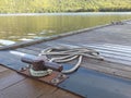 Rusty iron port bollard with rolled rope. Canadian lake.