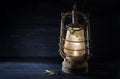 Rusty kerosene lantern shines undaunted with light in the dark, obsolete technology in times of modern energy-saving lamps,