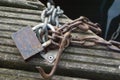 A rusty large lock with metallic massive chains on a wooden pear