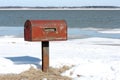 Rusty mailbox by frozen lake in winter landscape Royalty Free Stock Photo