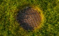 A rusty manhole cover in the middle of a grass field Royalty Free Stock Photo