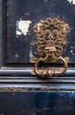 Rusty metal door handle with a patterned base on a dark blue old flaky front door Royalty Free Stock Photo