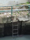 Rusty metal fence and ladder beside a dirty canal